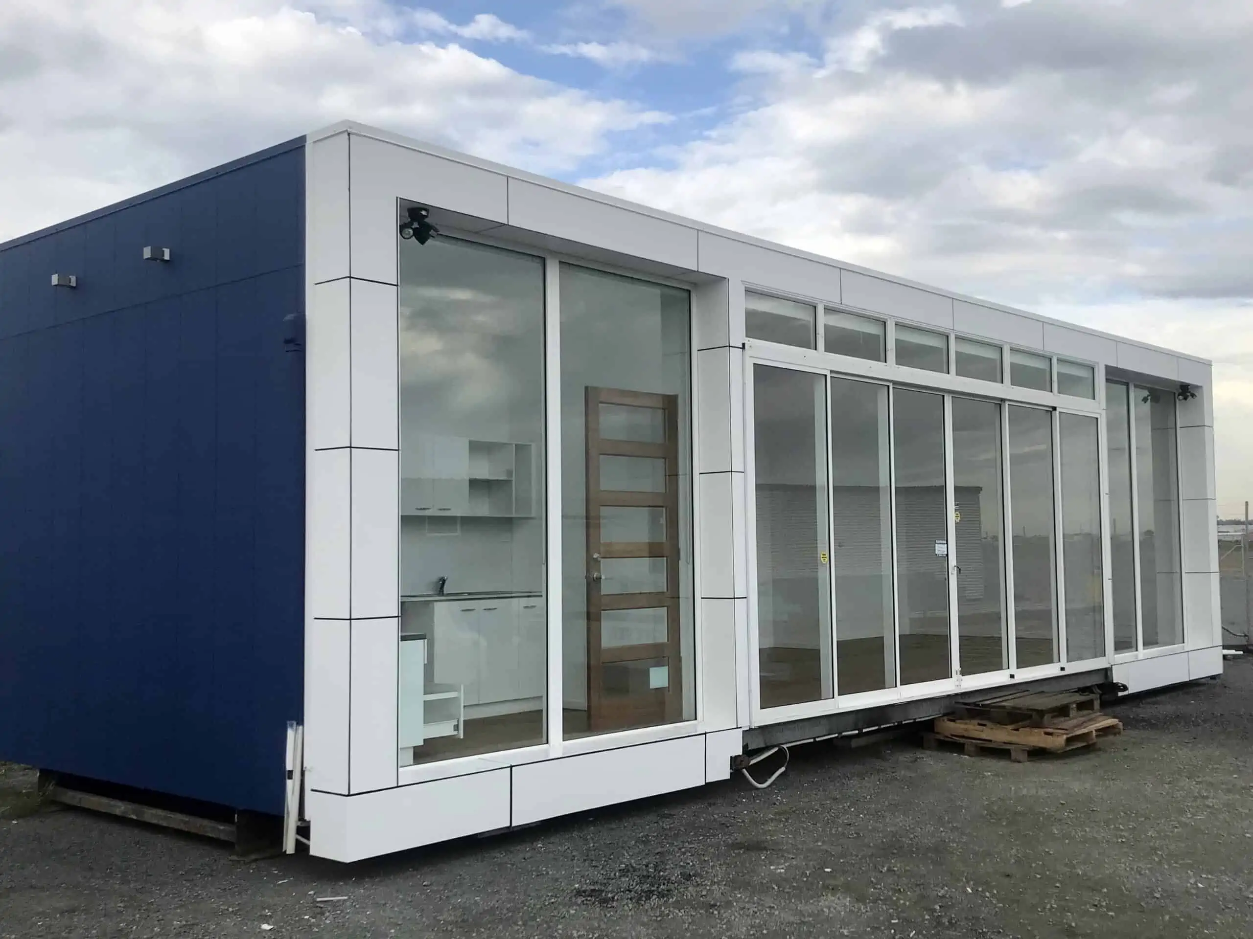 White modern marketing suite modular with windows and a dark blue exterior wall