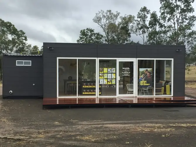 Dark grey modular building with a wooden glazed patio