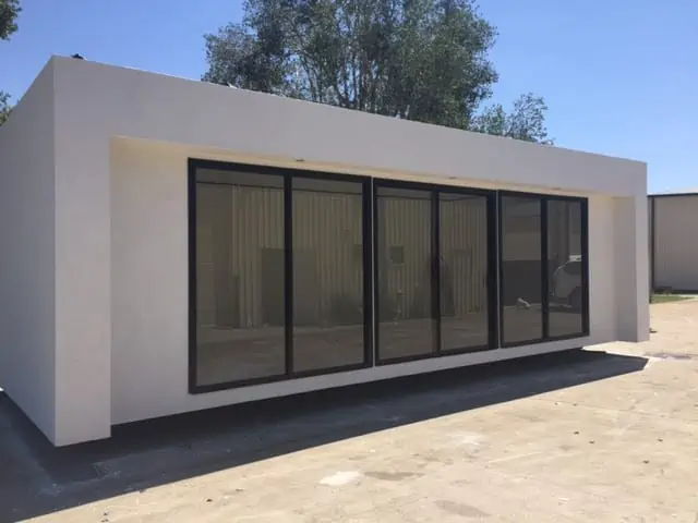 Modern white modular building with black framed glass doors