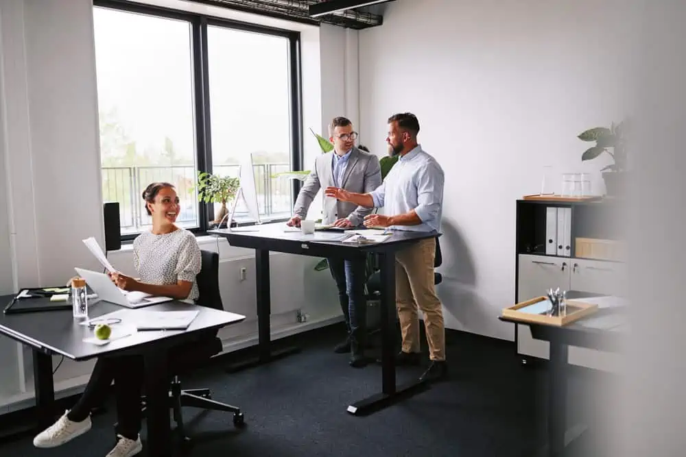 Group of smiling young business people working together at their desks